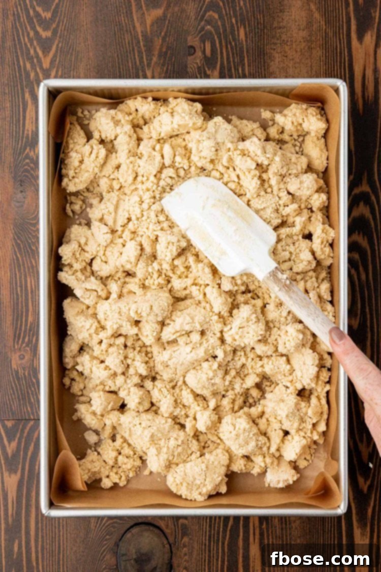 Shortbread cookie dough in a pan being pressed with a rubber spatula.