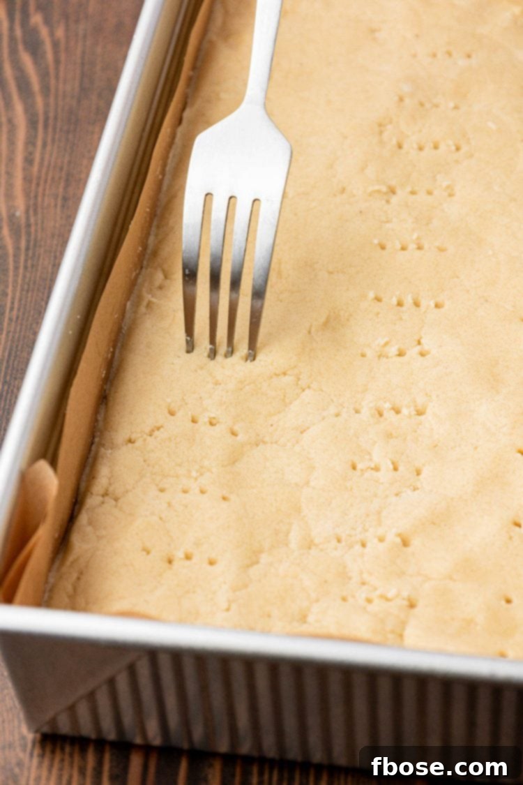 A fork poking shortbread dough all over. 