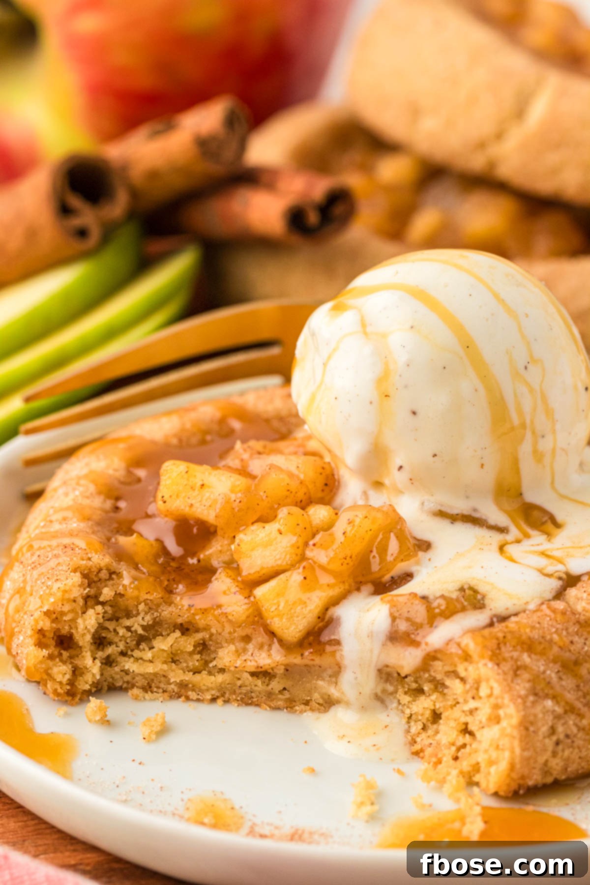 An apple pie cookie with a bite missing on a white plate.
