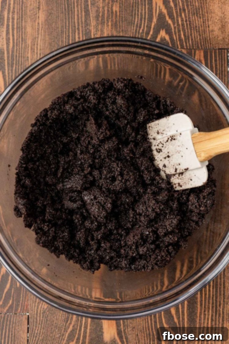 Gourmet Coffee Cheesecake 5 Oreo crust mixture being mixed in a glass bowl.
