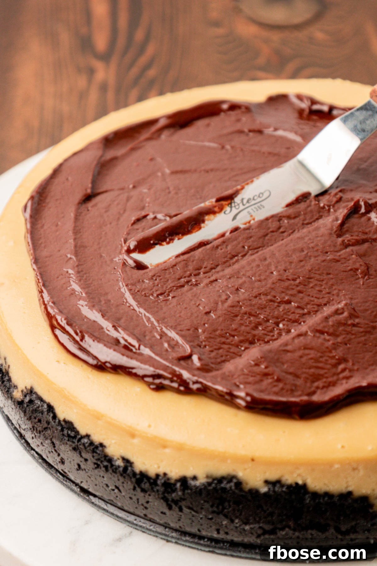 Gourmet Coffee Cheesecake 8 Chocolate ganache being spread over the top of a coffee cheesecake.