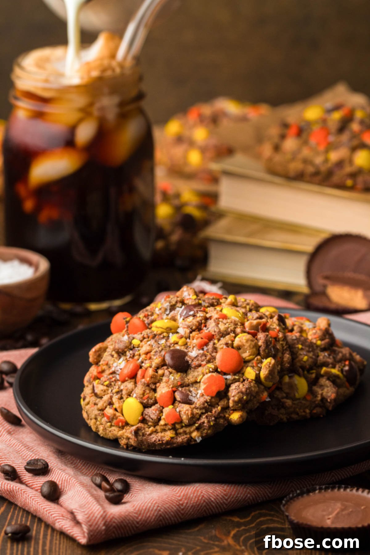 A black plate holding two Gideon's Bakehouse Peanut Butter Cold Brew Cookies, showing off their generous size and candy crust.