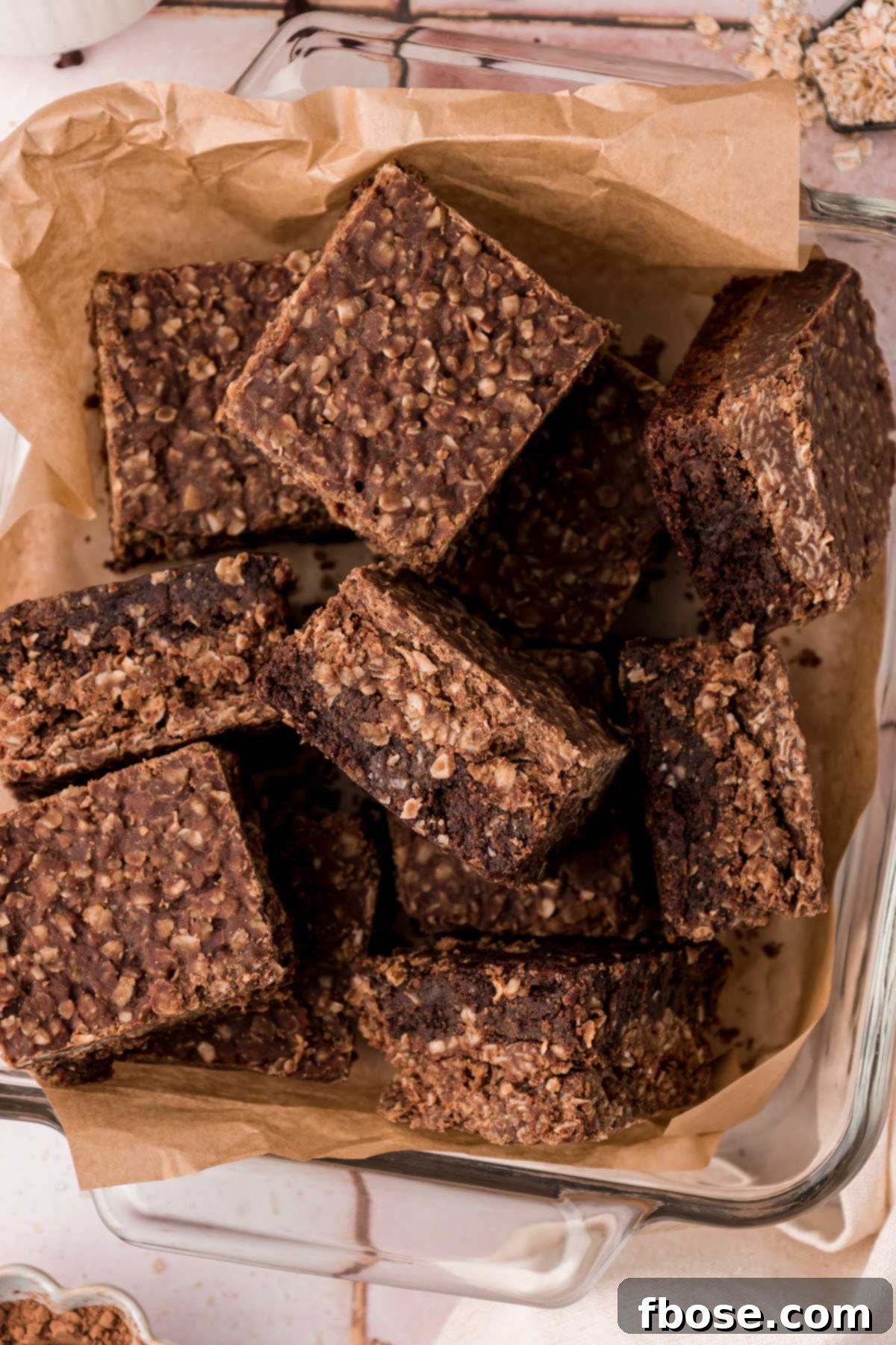 Effortless Fudgy Cookie Brownie Bars 8 Overhead photo of no bake cookie brownies in a pan with parchment paper.