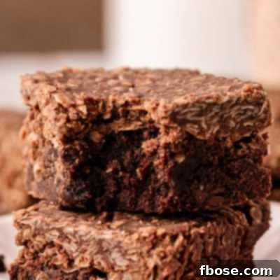 Effortless Fudgy Cookie Brownie Bars 10 No Bake Cookie Brownies stacked with the top one missing a bite.