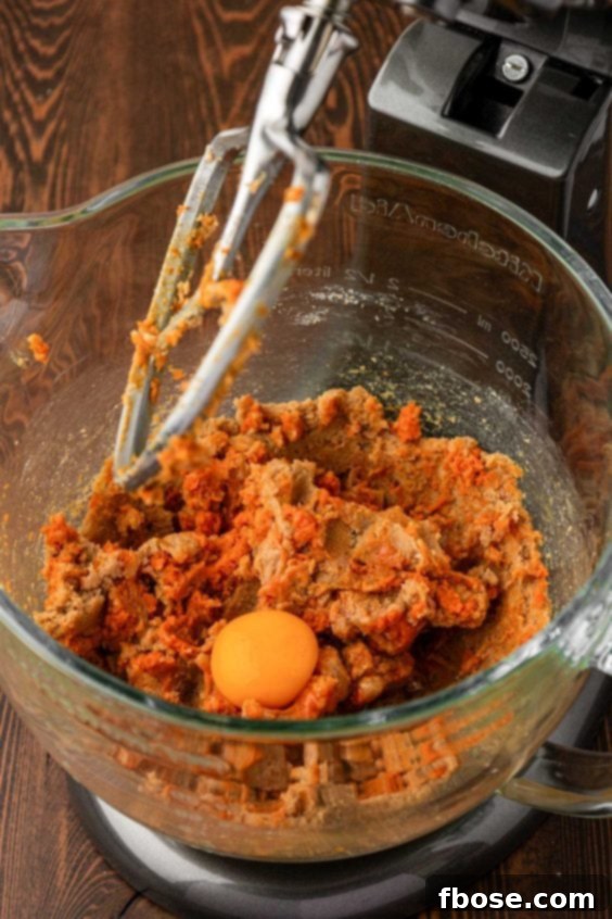 Egg being added to pumpkin cookie dough.