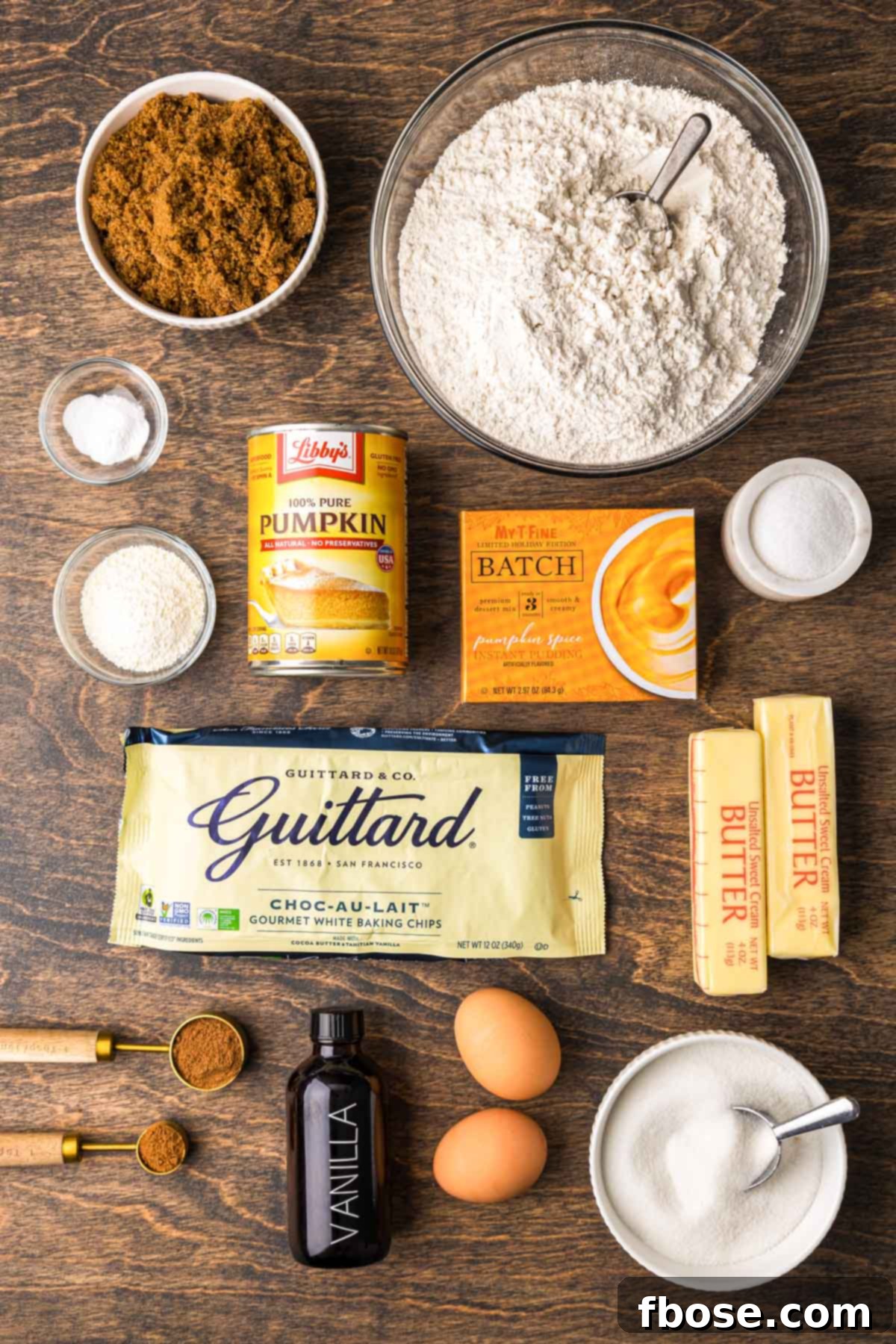 Ingredients to make pumpkin white chocolate chip cookies beautifully arranged on a wooden table.
