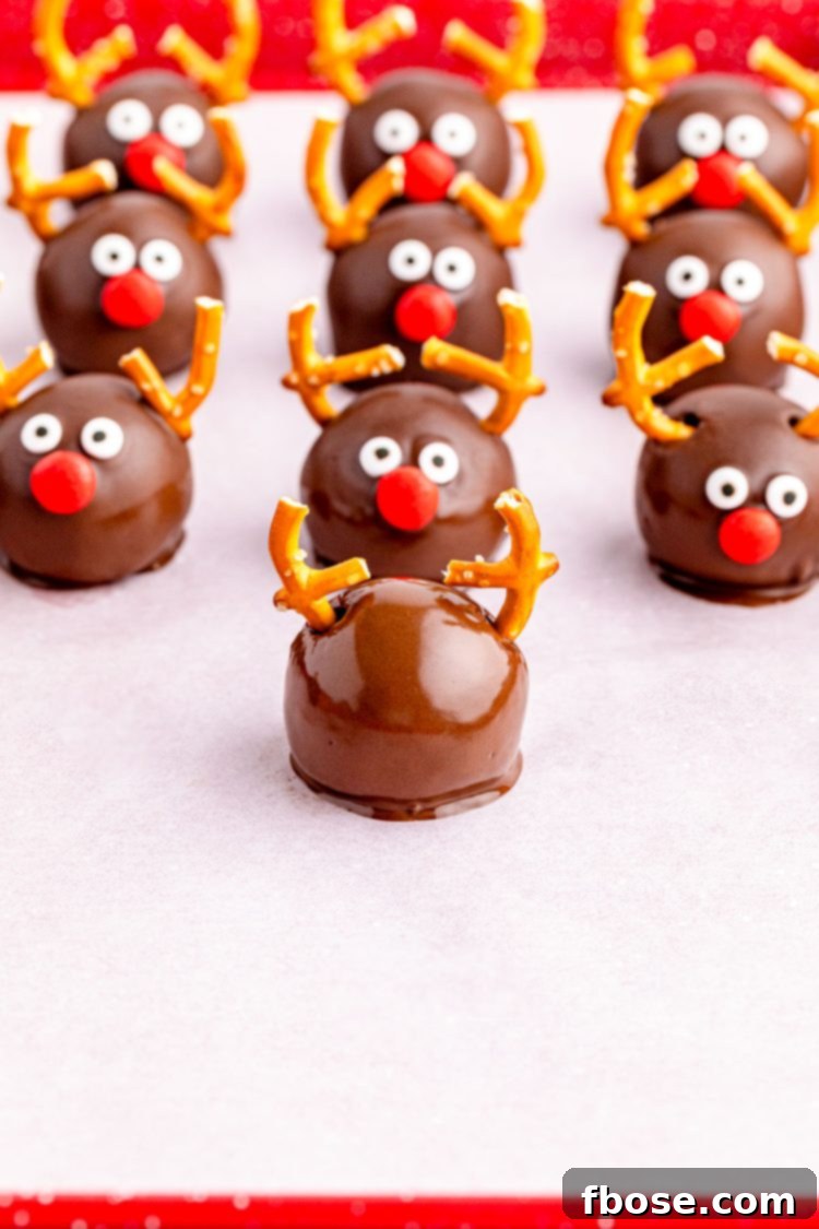 Reindeer Oreo Balls being assembled step-by-step on a parchment-lined baking sheet, showing pretzels added.