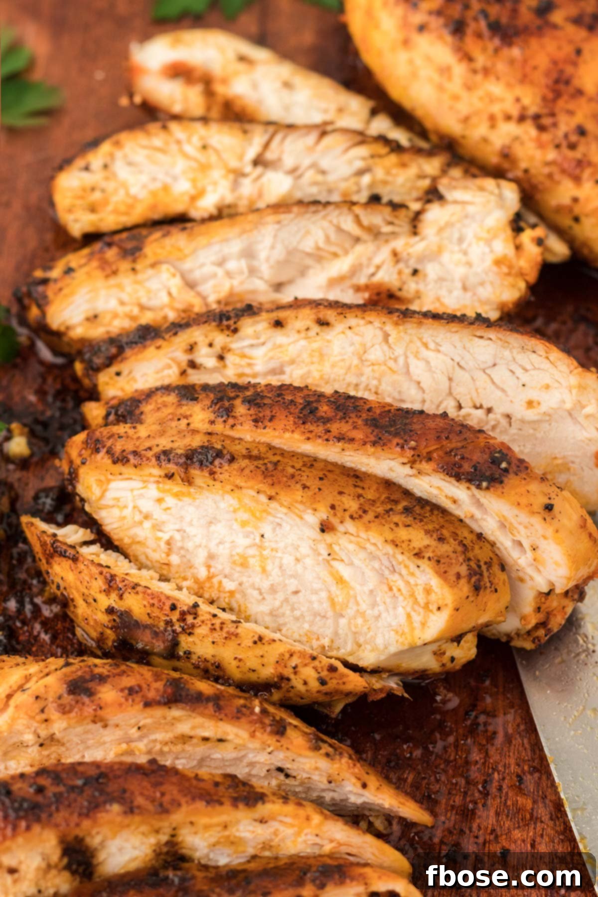 Perfectly cooked Juicy Chicken Breasts sliced up on a wooden cutting board, ready for a meal.