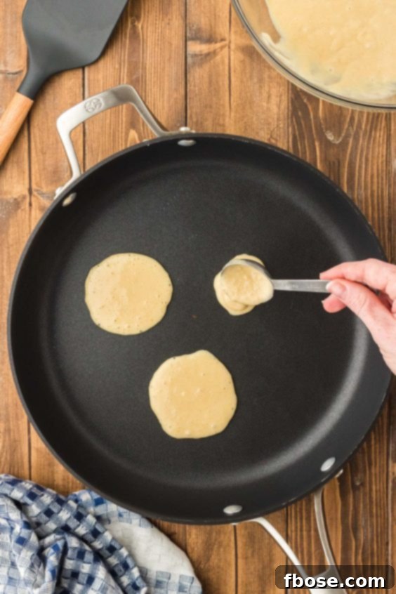 Fluffy Coin Pancakes 14 Pancake batter being spooned onto a skillet.