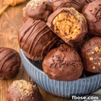 No-Bake Peanut Butter Crunch Bites 13 A blue bowl brimming with chocolate-coated Peanut Butter Balls, one with a bite taken out, showcasing the crispy interior.