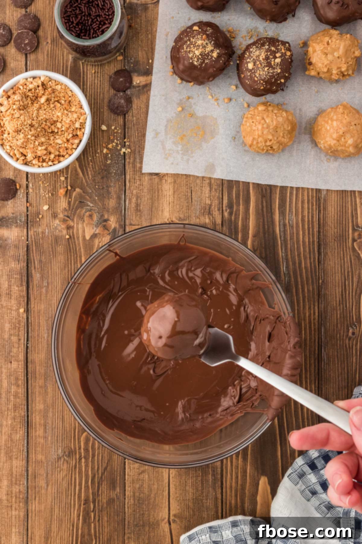 No-Bake Peanut Butter Crunch Bites 9 A Rice Krispie Peanut Butter Ball is carefully being dipped into a bowl of perfectly melted chocolate, ensuring a smooth and even coating.