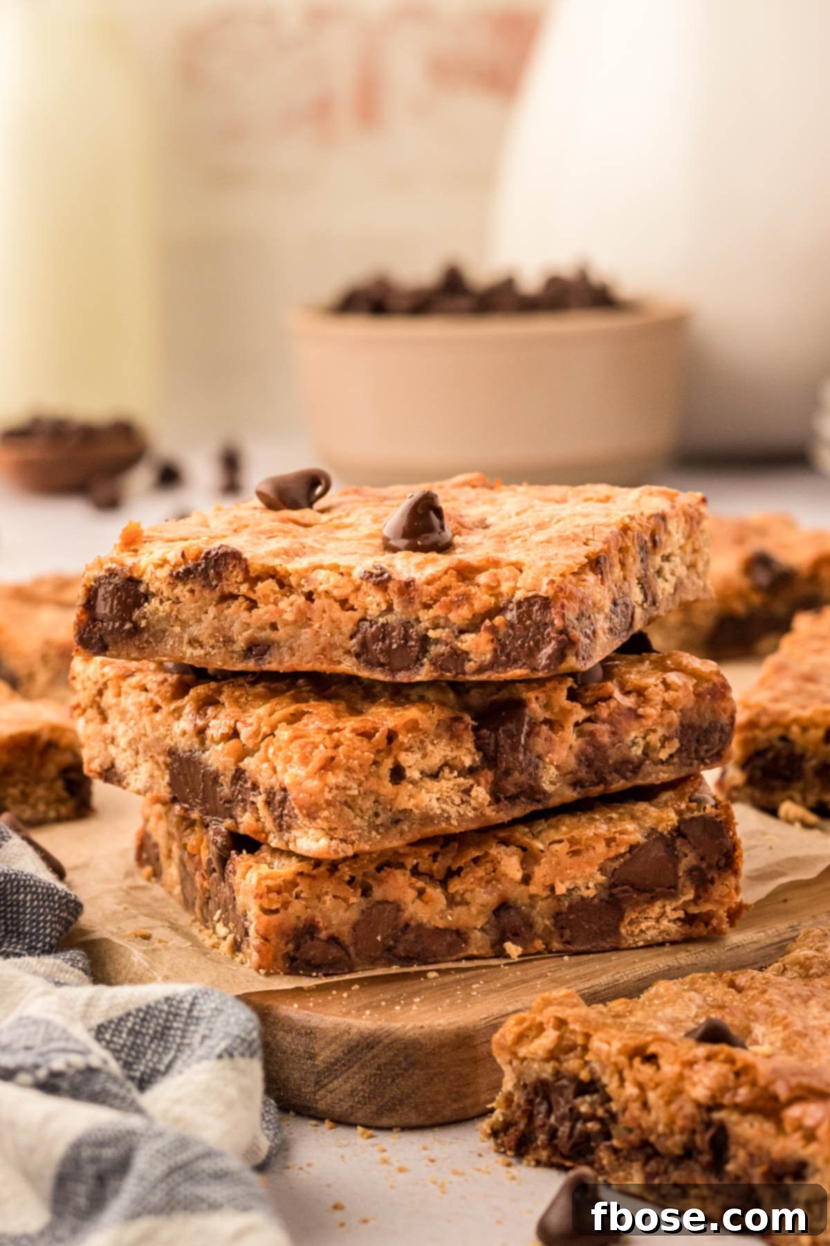 A stack of three golden brown graham cracker bars, topped with melted chocolate chips, resting on a rustic wooden board.