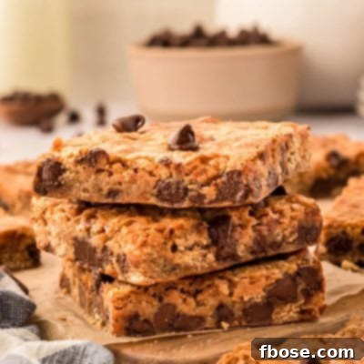 A stack of three golden brown graham cracker bars, topped with melted chocolate chips, resting on a rustic wooden board.