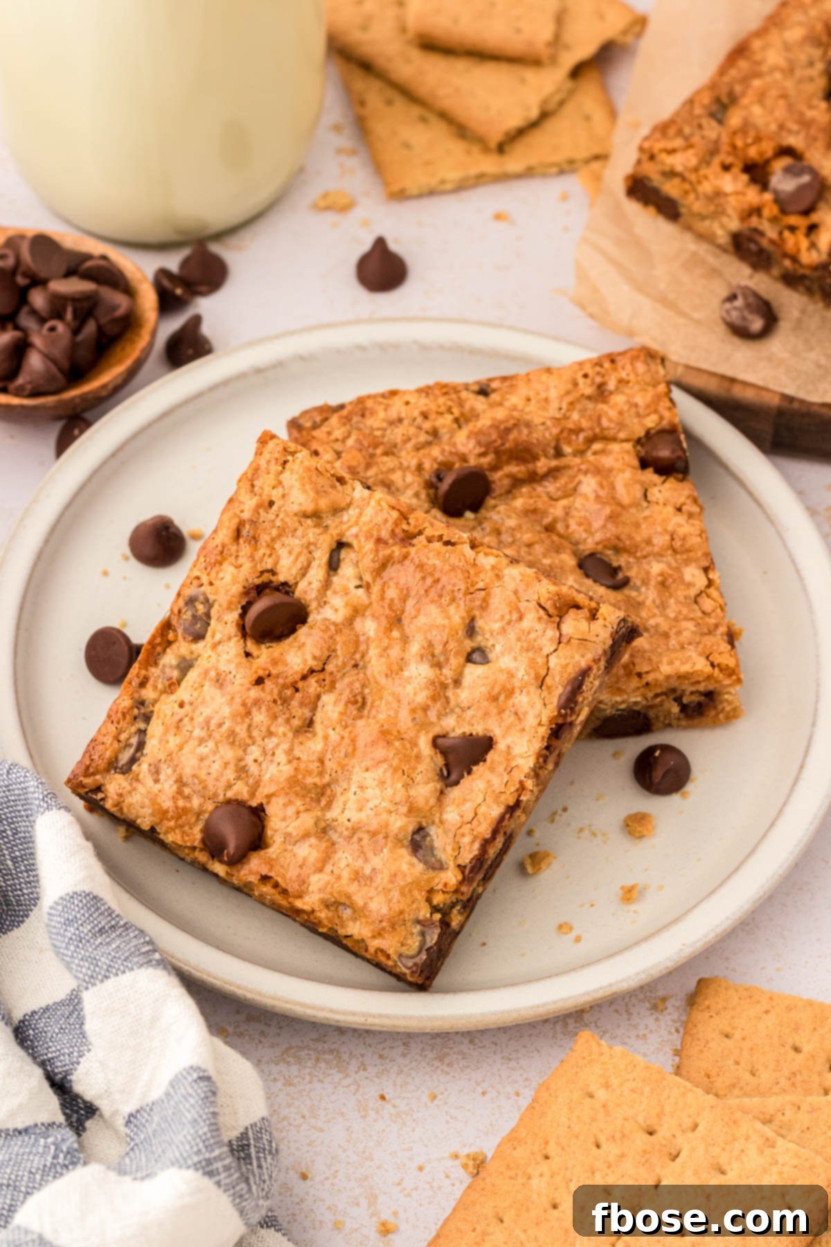 Two freshly baked graham cracker bars, glistening with melted chocolate, presented neatly on a white plate, ready to be enjoyed.