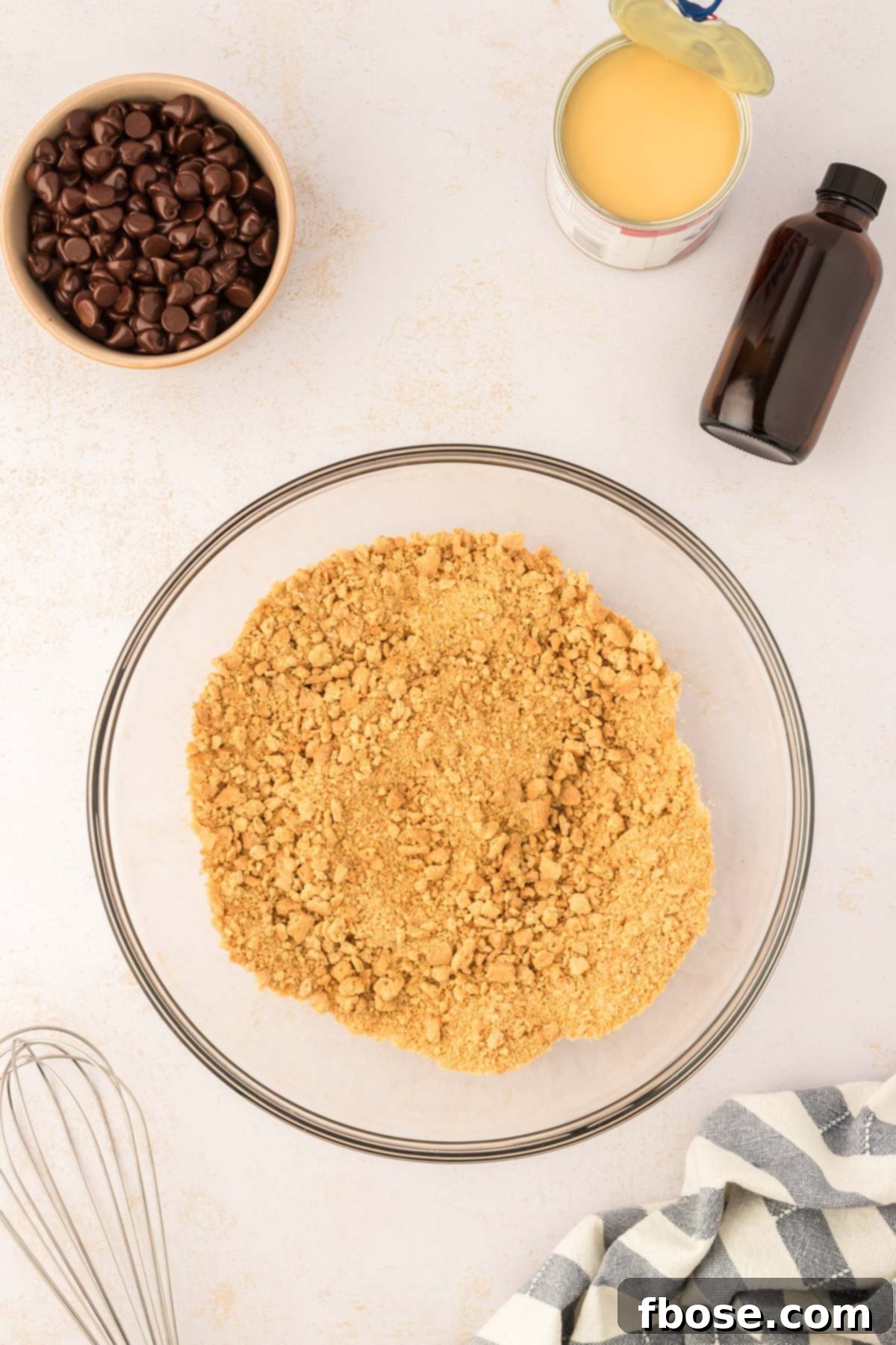 A large glass bowl filled with finely crushed graham cracker crumbs, ready for the addition of other ingredients.