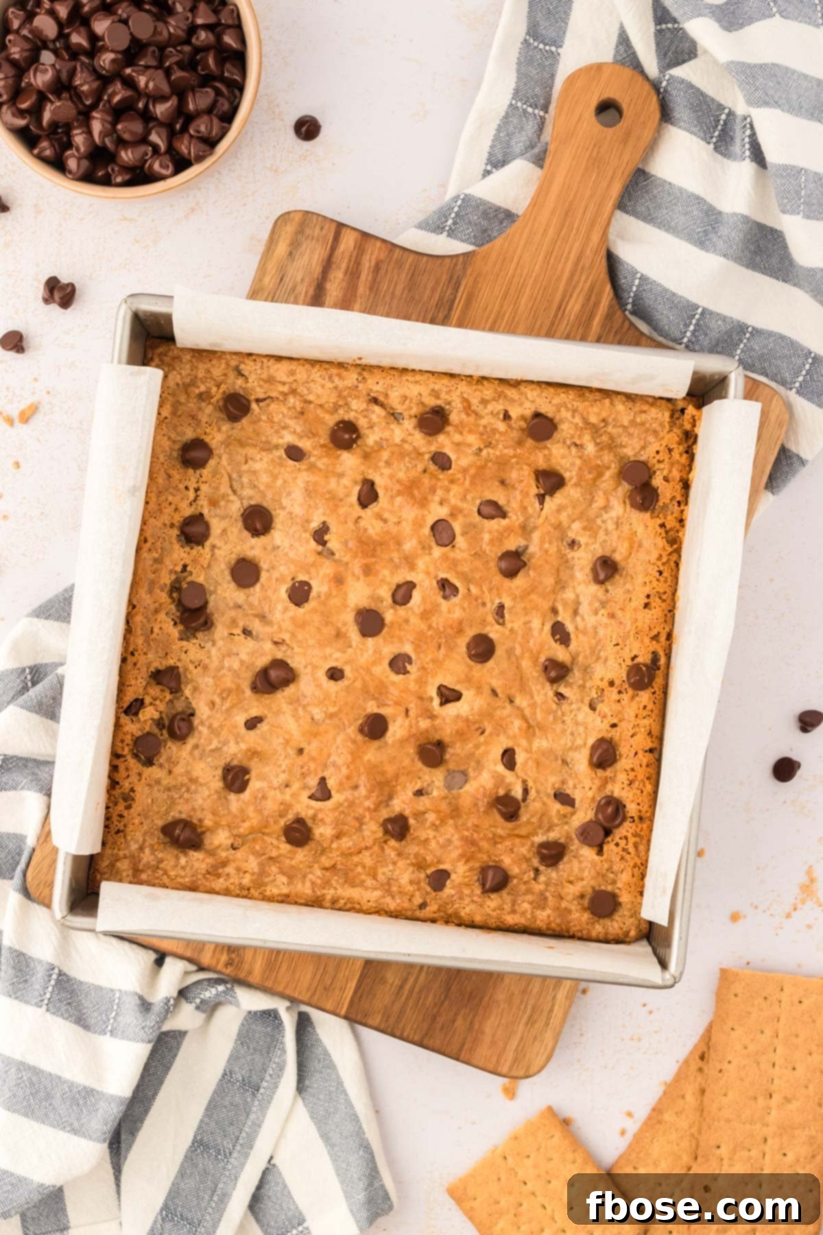 An overhead photo of perfectly baked graham cracker bars cooling in a parchment-lined baking pan, demonstrating the final stage before slicing.