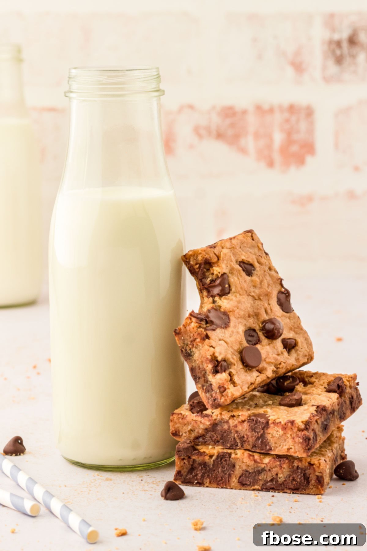 A charming stack of graham cracker bars next to a bottle of milk, with the top bar artfully leaning against it and showing a bite taken out.