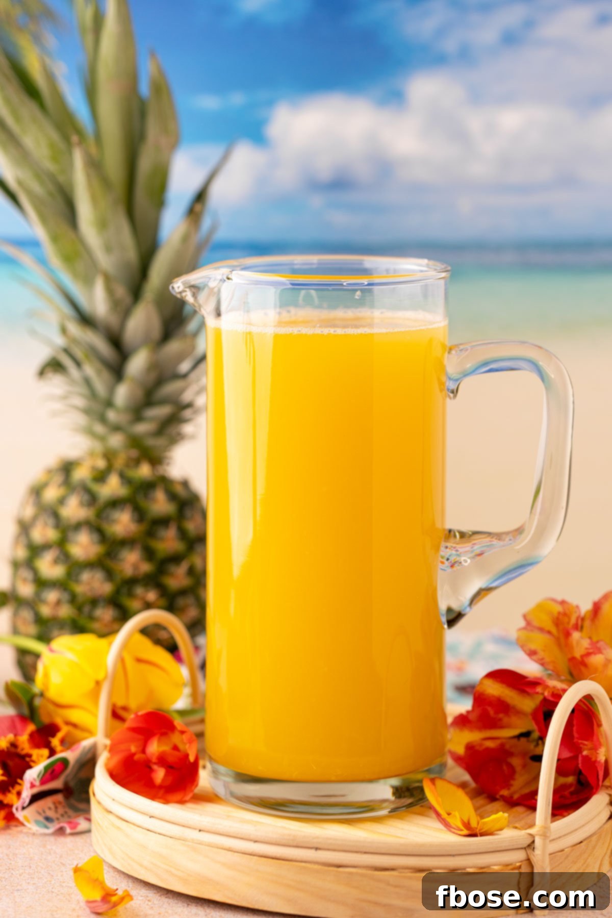 A large pitcher brimming with golden pineapple punch, ready to be served.