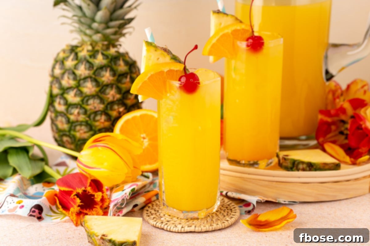 Two glasses and a pitcher of pineapple punch beautifully arranged against a beach backdrop, promising a refreshing escape.