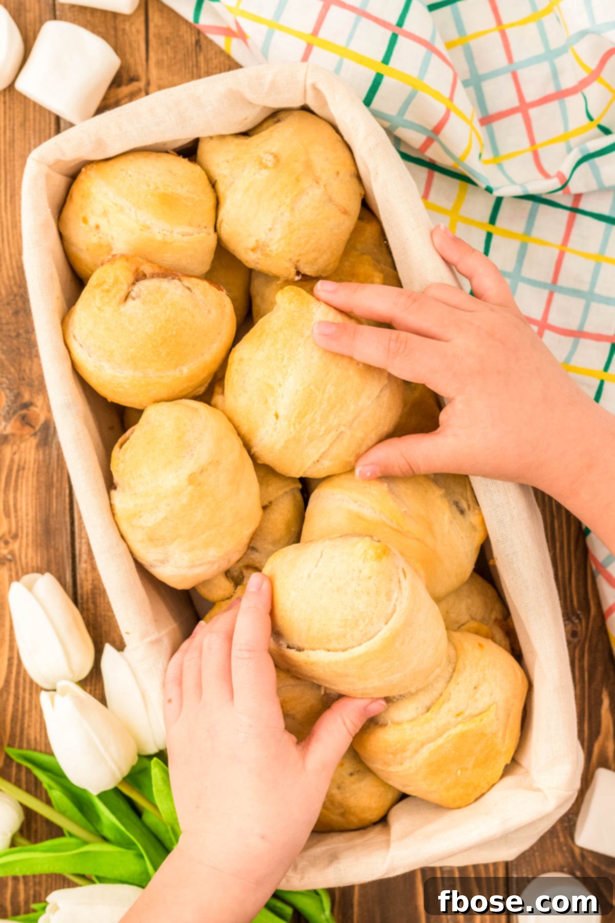 Toddler hands grabbing resurrection rolls out of a basket at Easter.