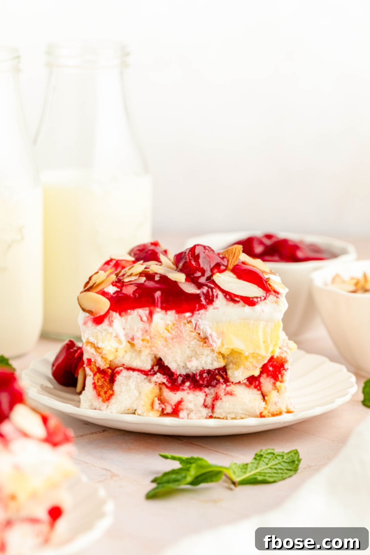 A pristine slice of Heaven on Earth cake, generously topped with strawberries, served on a white plate, highlighting its perfect layers.