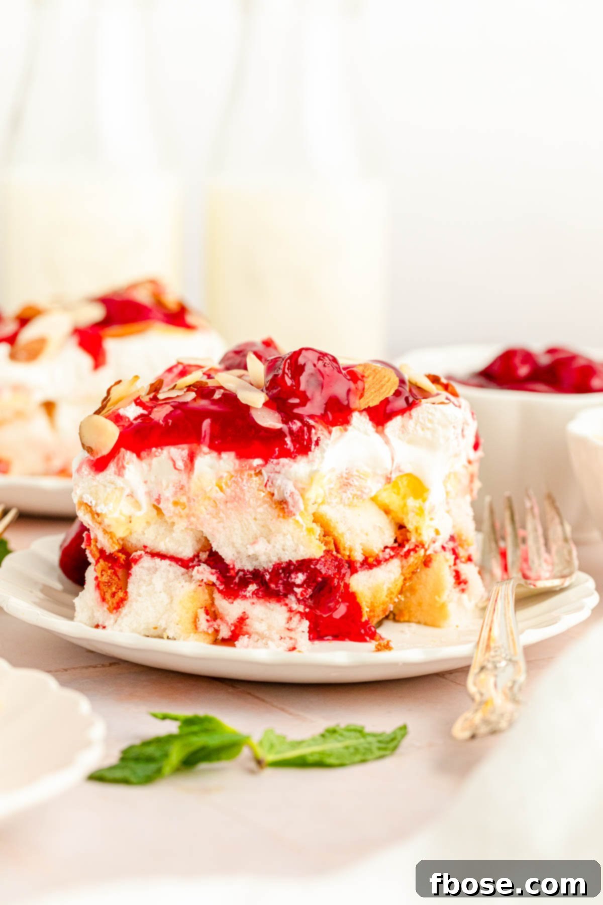 Another perspective of a slice of Heaven on Earth cake with strawberries on a white plate, showcasing the delicate balance of ingredients.
