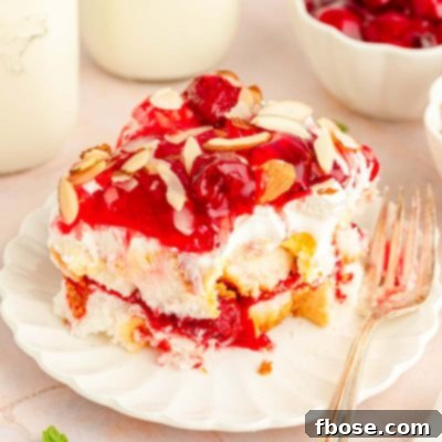 Close up of a slice of Heaven on Earth Cake made with strawberries on a white plate with a fork.