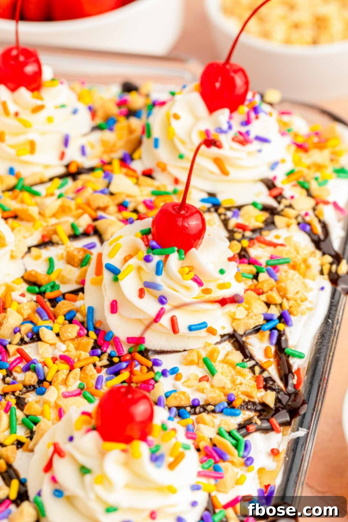 Close-up view of the layered no-bake banana split cake in a clear glass baking dish, showing the vibrant fruits and creamy white topping.