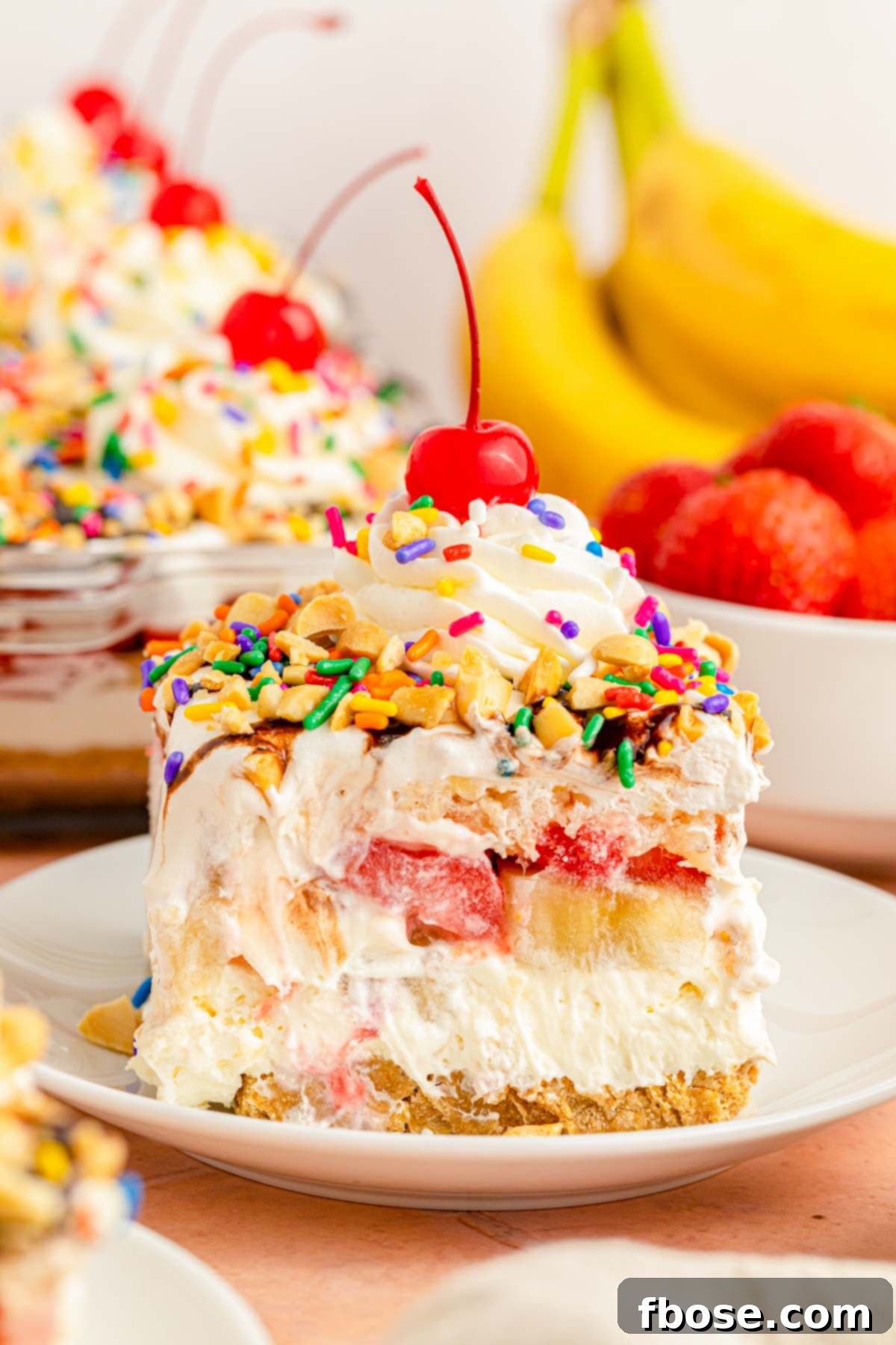 A pristine slice of no-bake banana split cheesecake on a white plate, ready to be enjoyed.
