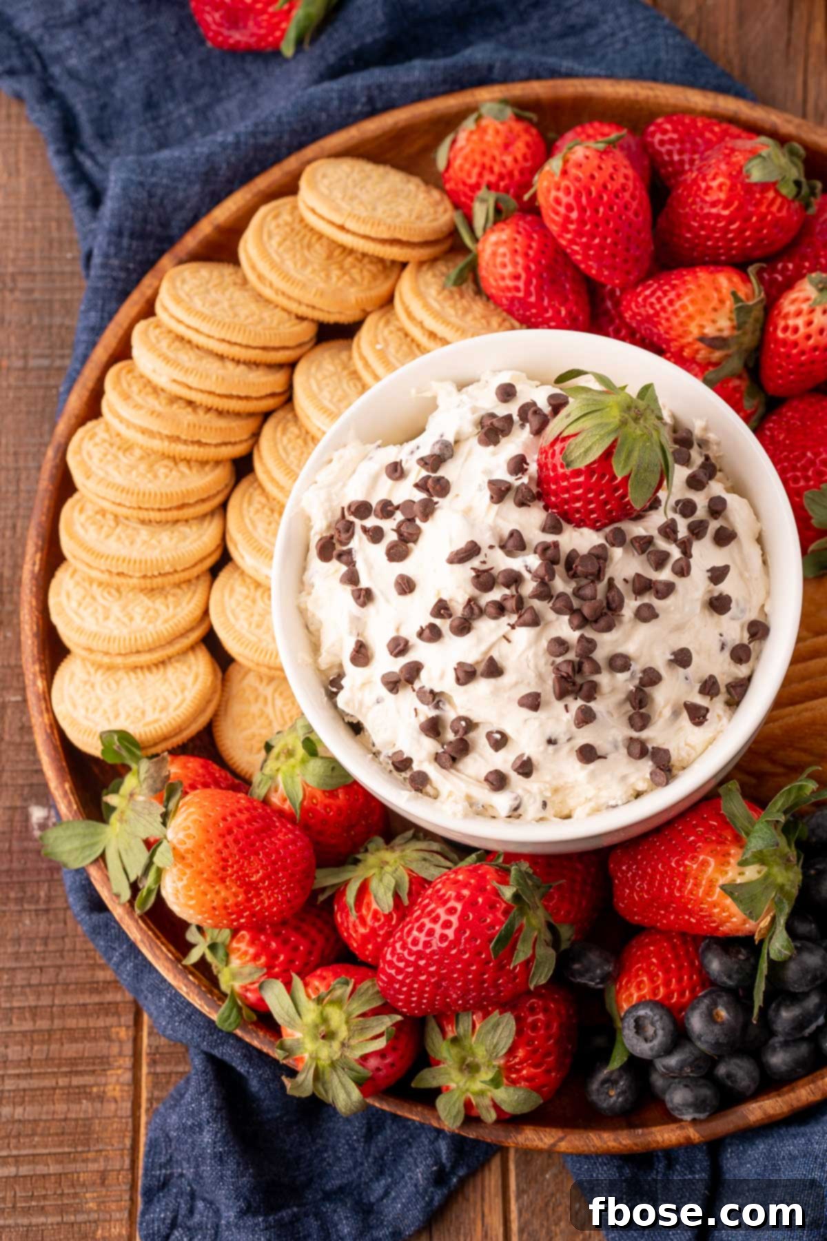 A beautifully arranged bowl of TikTok Booty Dip, served on a rustic platter alongside an assortment of fresh berries and gourmet cookies, inviting guests to dip and enjoy.