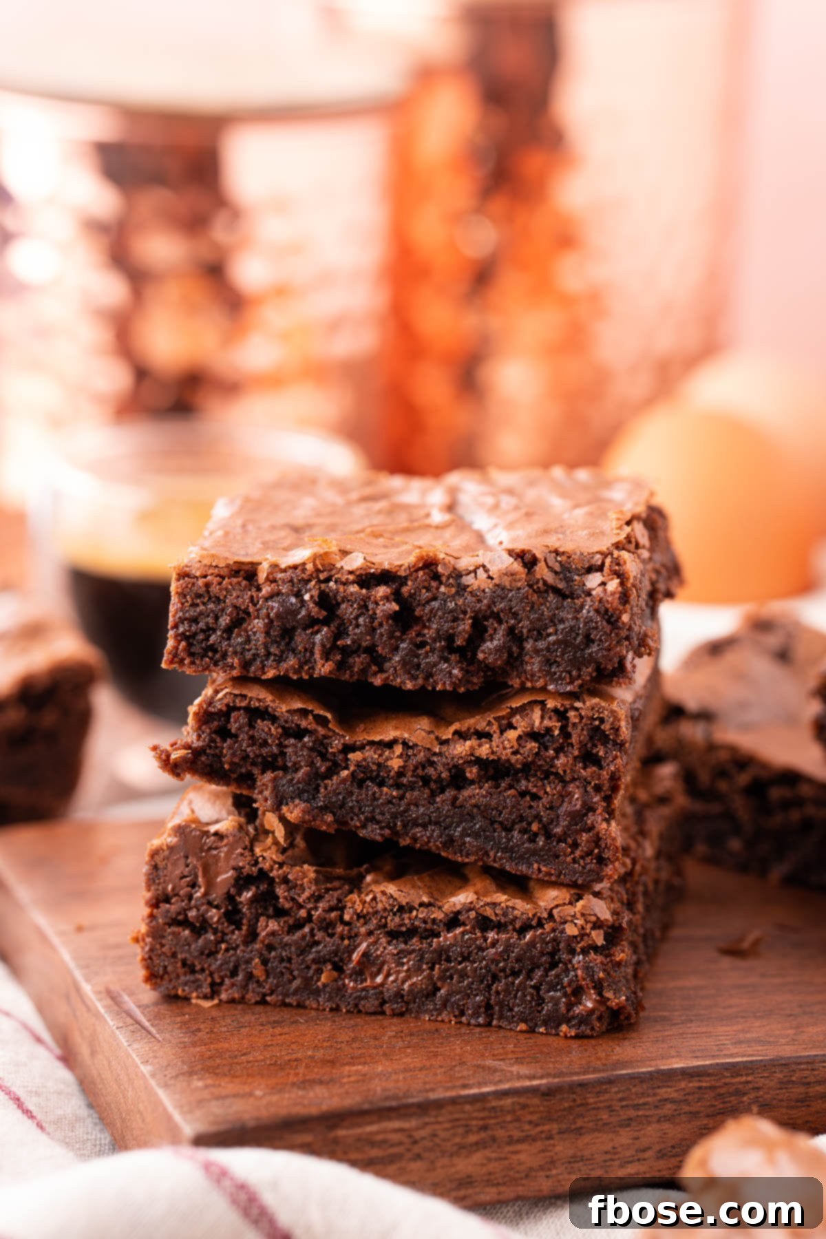 Three decadent box mix brownies, stacked beautifully, showcasing their fudgy texture and rich chocolate color on a rustic wooden board.