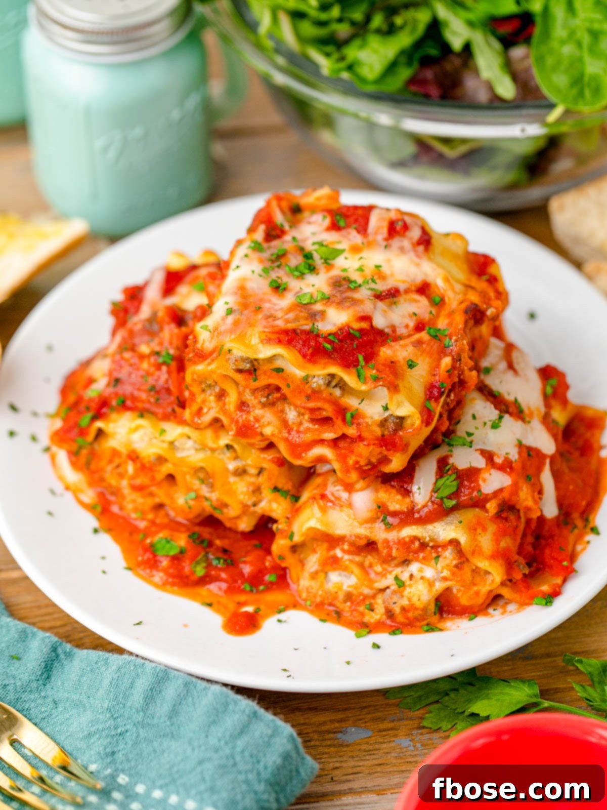 A beautifully set table featuring a plate of hot, garnished lasagna roll-ups, ready to be enjoyed as a comforting meal.