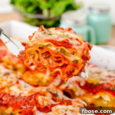 A close-up of a spatula scooping a lasagna roll-up out of a pan, showcasing its perfect bake.