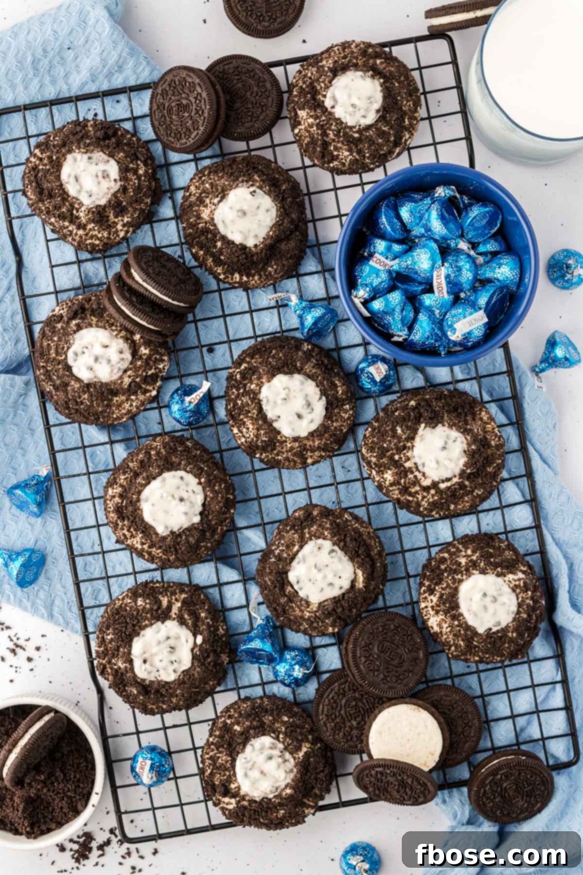 Overhead photo of multiple Oreo thumbprint cookies cooling on a wire rack after being baked and topped with Hershey's Kisses.