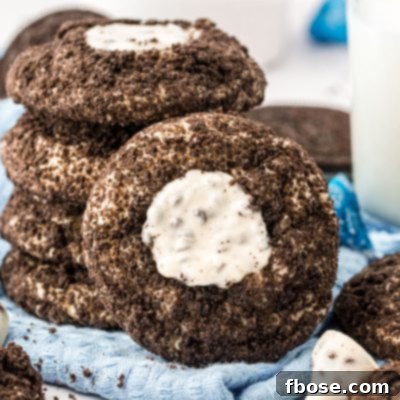 A stack of Oreo thumbprint cookies with one leaning against it.
