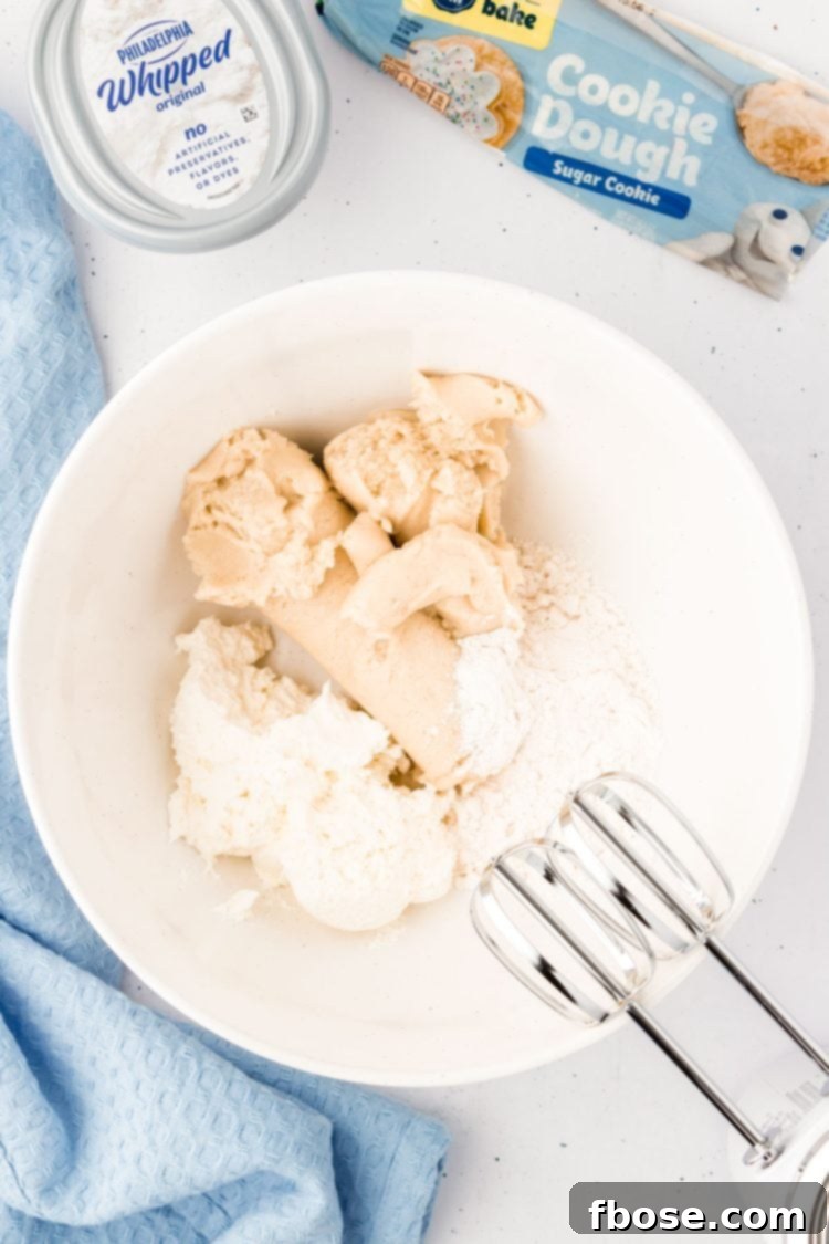 Cookie dough and cream cheese in a white bowl, perfectly mixed and ready for the next step.
