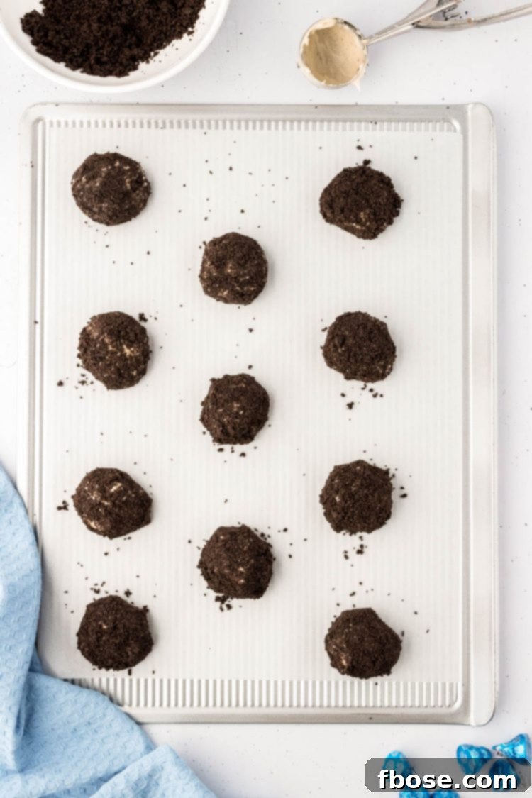 Cheesecake-like cookies, beautifully coated in Oreo crumbs, arranged on a parchment-lined baking sheet, freshly baked.