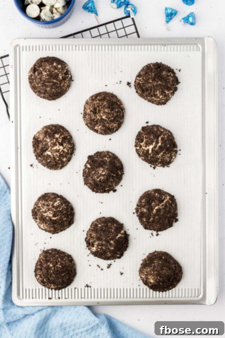 Overhead photo of a baking sheet filled with freshly baked Oreo thumbprint cookies, cooling down.