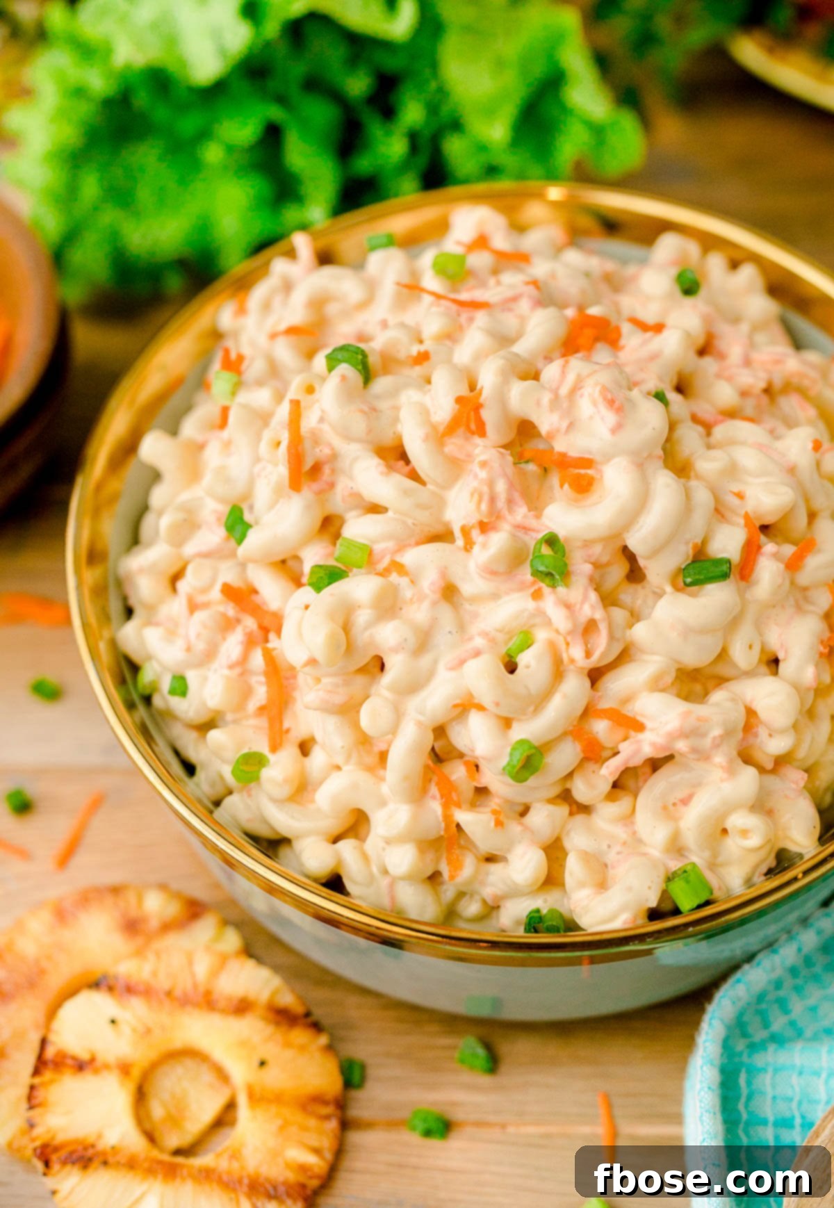 A bowl of Hawaiian macaroni salad on a wooden table, garnished beautifully.