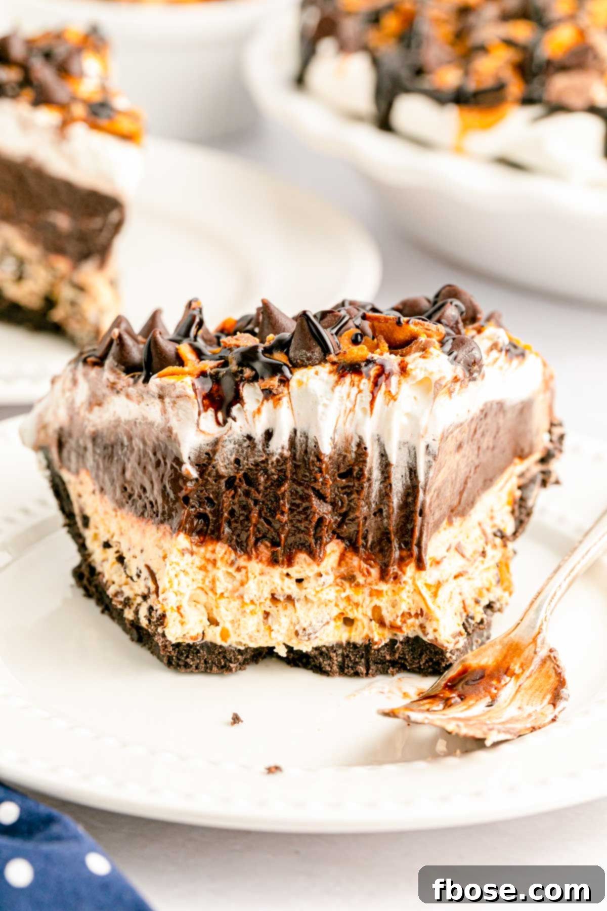 A tempting slice of Butterfinger pie on a white plate, with a few delicious bites already taken, highlighting the irresistible layers and crunchy candy topping.