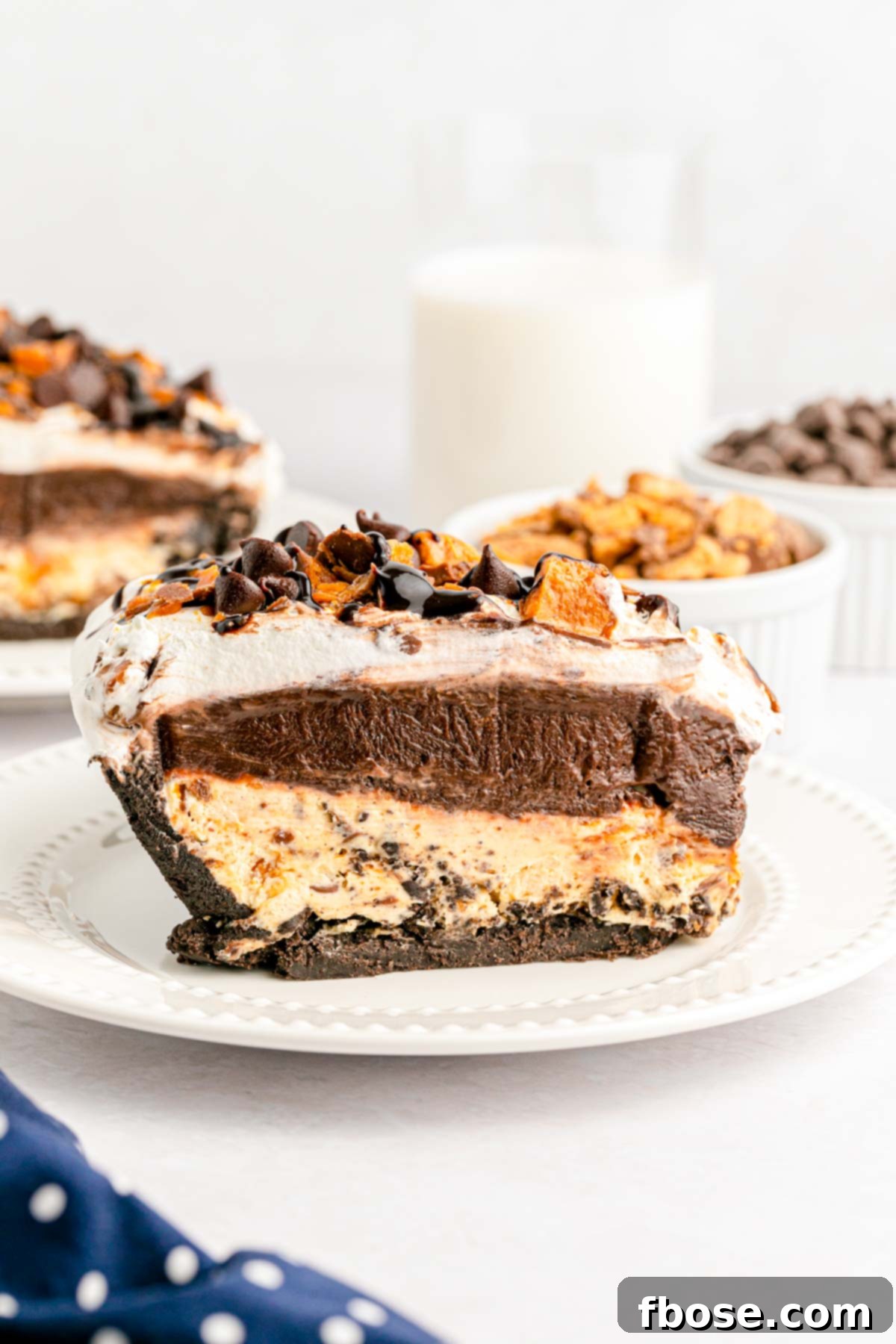 A beautiful side view of a slice of Butterfinger peanut butter pie, showing all the decadent layers and crunchy candy bar bits.