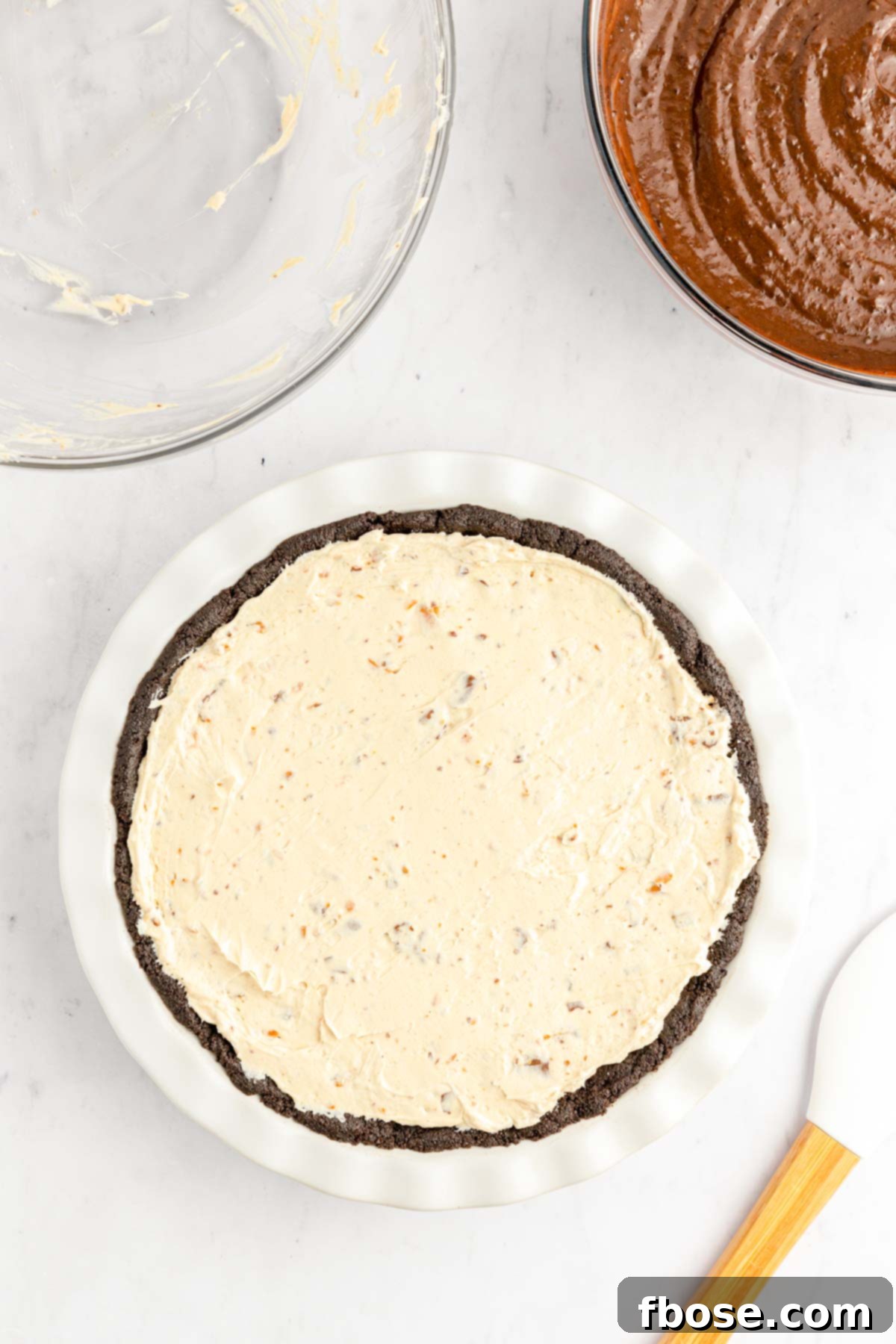 The creamy Butterfinger peanut butter pie filling, spread smoothly over the chocolate Oreo crust in a white pie dish.