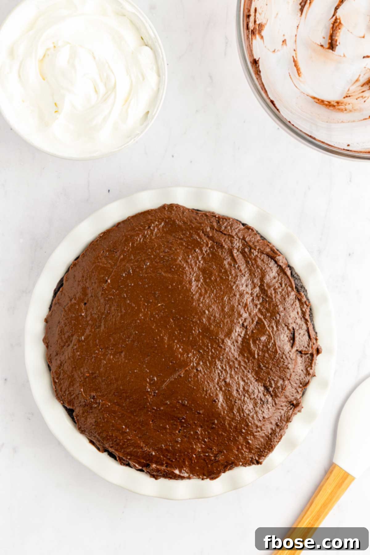 A smooth layer of rich chocolate pudding, perfectly spread over the pie's previous layers, ready for its final toppings.