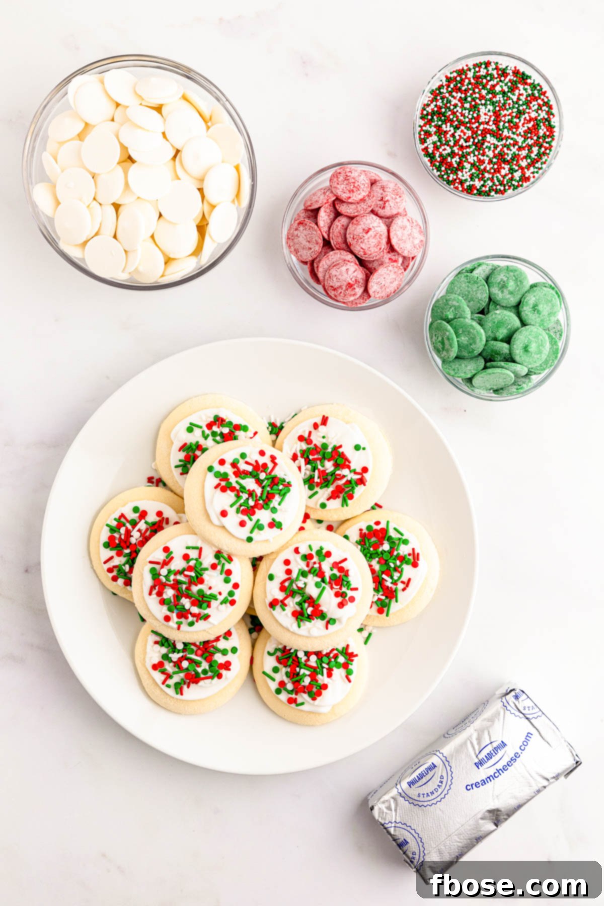 Overhead photo of sugar cookie truffle ingredients laid out: Lofthouse cookies, cream cheese, white chocolate wafers, and sprinkles.
