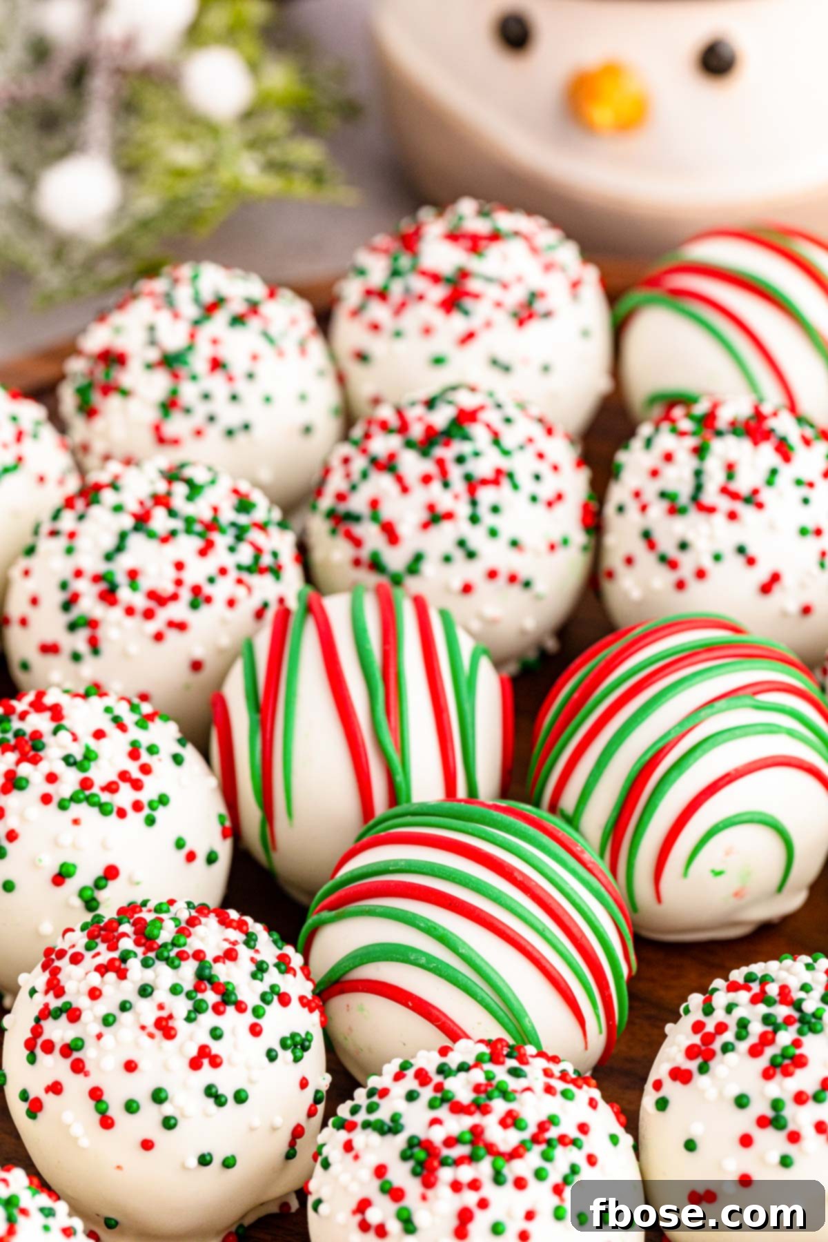 Sugar cookie truffles decorated for Christmas with red and green drizzles, presented on a festive plate.