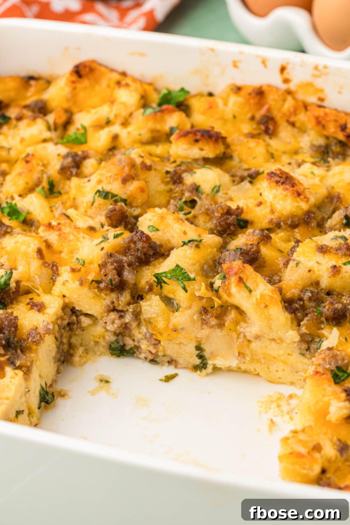 A close-up shot of the finished Overnight Breakfast Sausage Strata in a baking pan, with one slice already removed, showing its delicious layers.