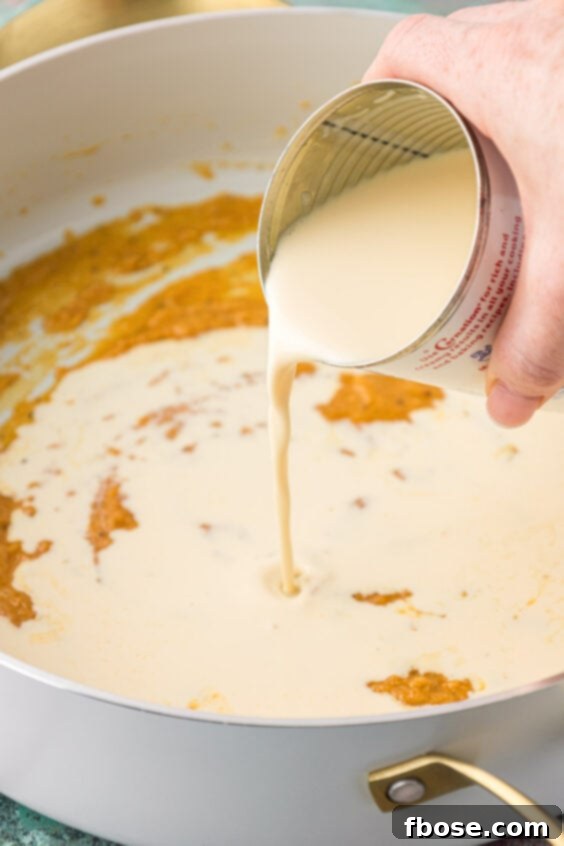 Evaporated milk being poured into a skillet with roux, to create the mac and cheese sauce.