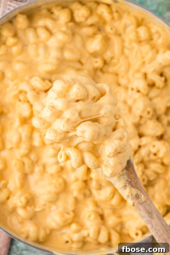 Overhead photo of creamy mac and cheese being stirred in a skillet, ready for layering.