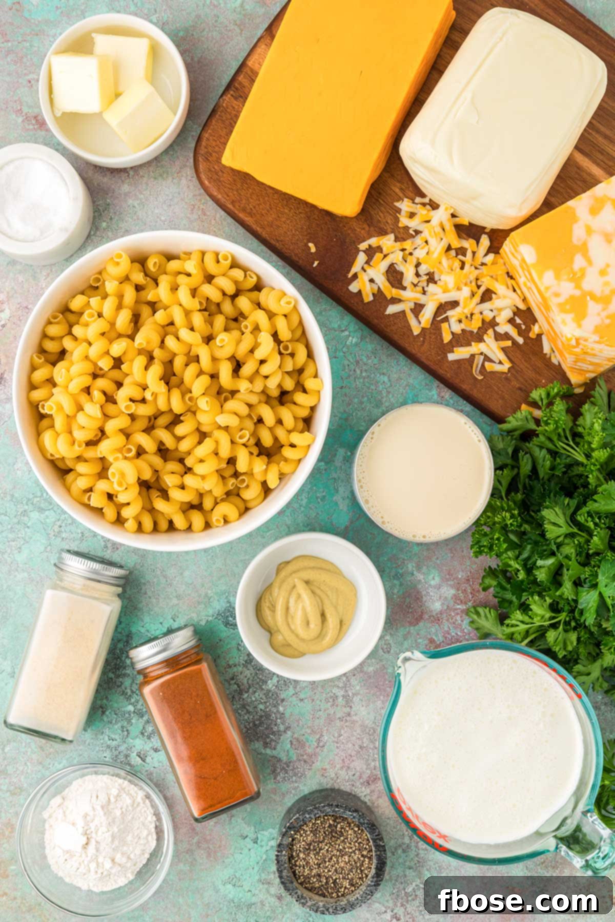 Overhead photo of various ingredients beautifully arranged on a wooden table, ready to make mac and cheese.