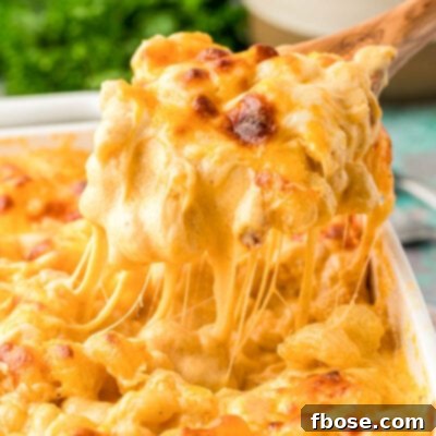 A serving spoon scooping mac and cheese out of a casserole dish, highlighting its rich texture.